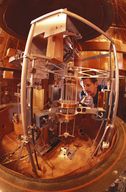 A scientist places a kilogram artifact on a balance pan in the watt balance experiment