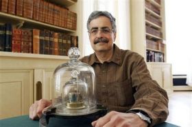 Richard Davis of the International Bureau of Weights and Measures, sits next to a copy of the cylinder that has been the international prototype for the metric mass, in his office in Sevres.