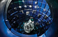 Inside the National Ignition Facility, a service system lift gives technicians access to the target chamber interior for inspection and maintenance. The chamber is a sphere 10 meters in diameter, assembled from ten-centimeter-thick aluminum panels which were preformed and then welded in place. It is covered with .3 meters of concrete which was injected with boron to absorb neutrons from the fusion reaction. The holes in the chamber permit the 192 laser beams to enter the chamber and to provide viewing ports for diagnostic tools.